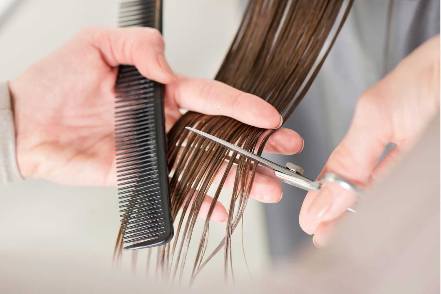 Hair being trimmed with scissors and comb in a close-up shot.
