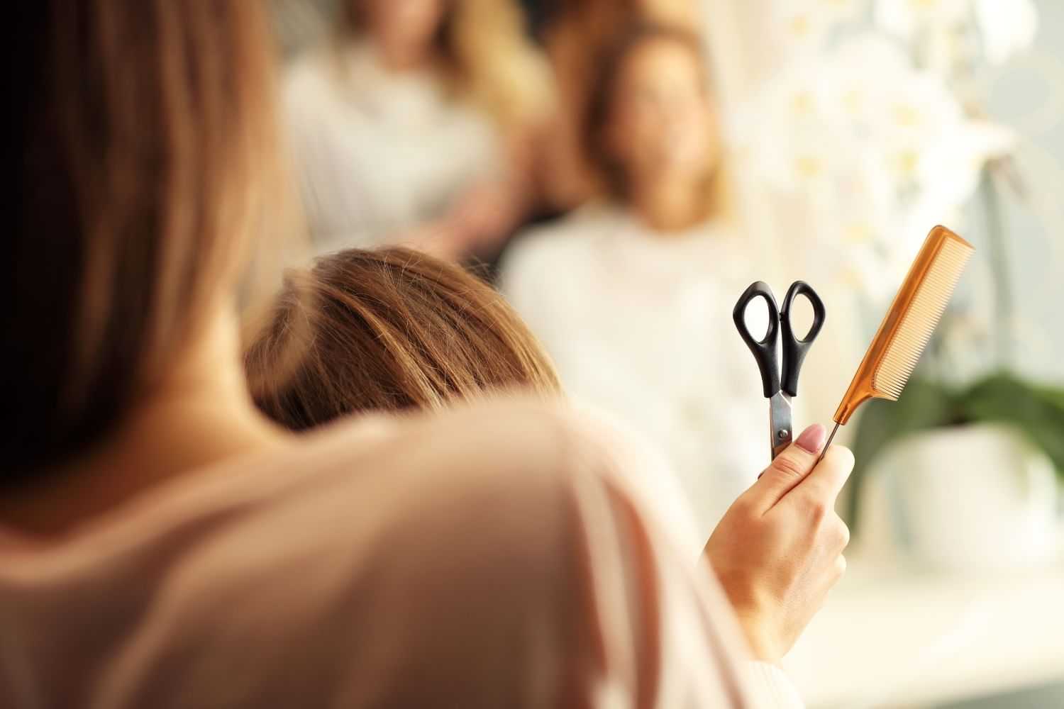 Hairdresser holding scissors and comb, preparing for a haircut in a salon.